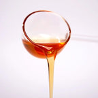 Close-up of lemon concentrated syrup pouring, featuring a clear golden amber color and zesty citrus texture.